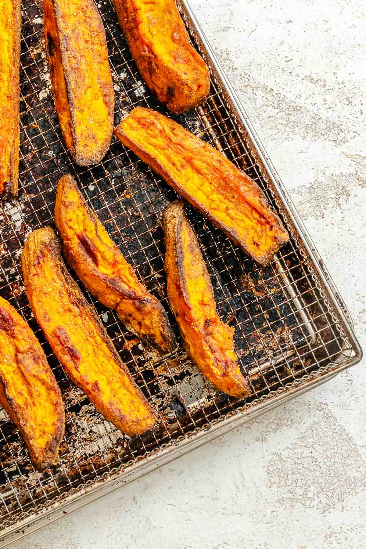 Process shot showing post air fried wedges on air fryer tray.