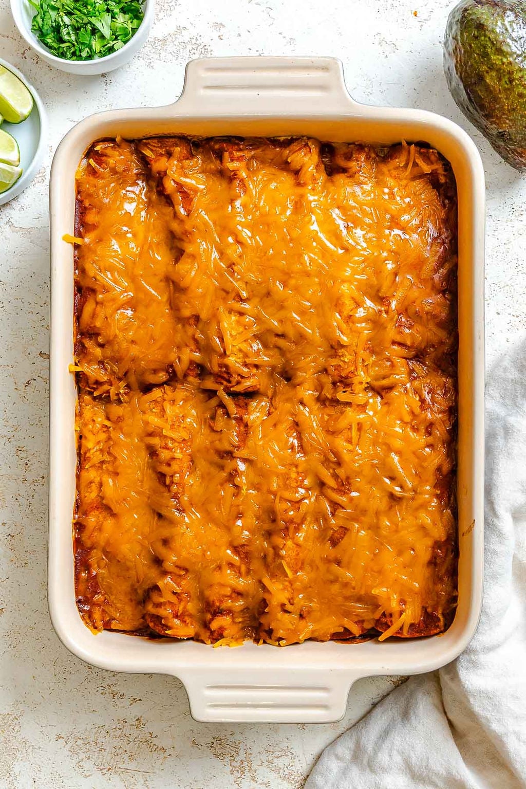 Process shot showing post baked vegan enchiladas in baking dish.