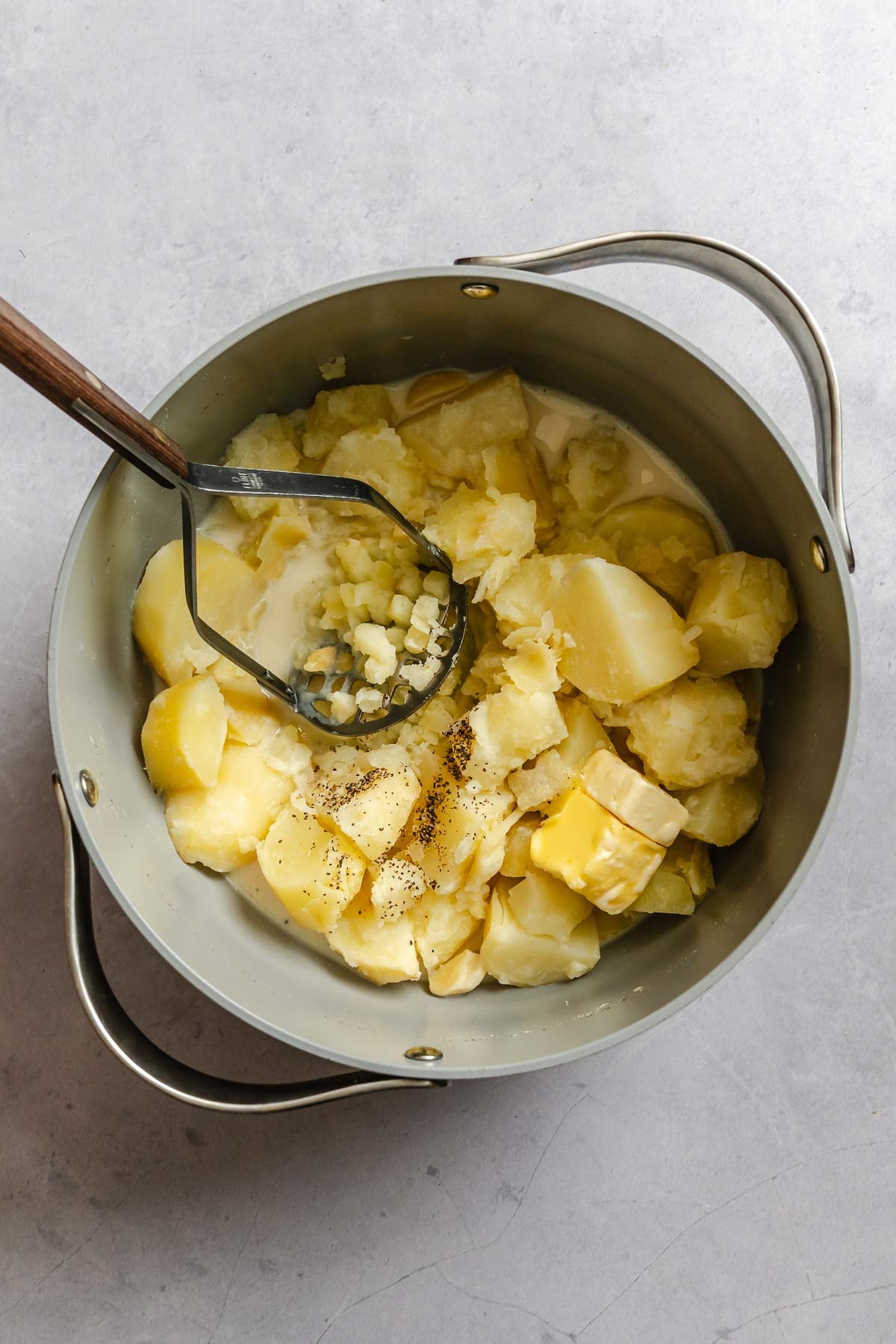 Process shot showing mashing potatoes in pot.