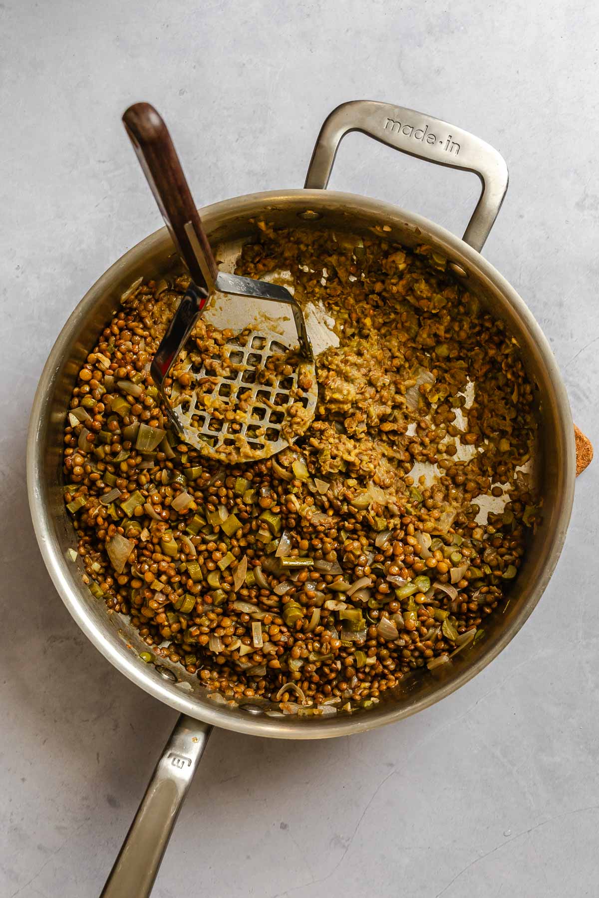 Process shot showing adding lentils to pot.