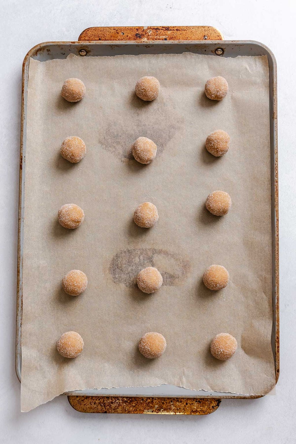 Process shot showing adding cookie dough balls to baking sheet.