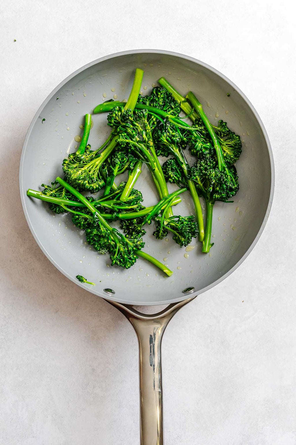 Process shot showing cooking broccolini in a pan.