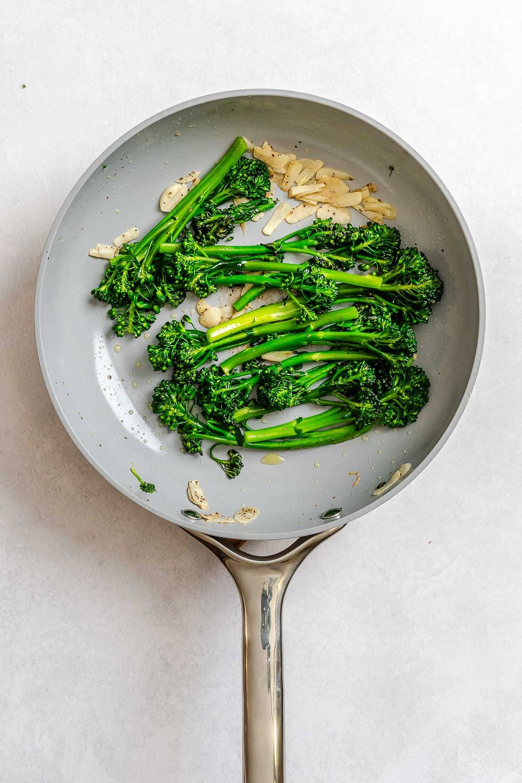 Process shot showing cooking broccolini in a pan.