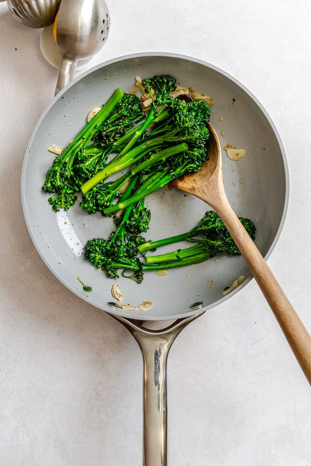 Process shot showing cooking broccolini in a pan.