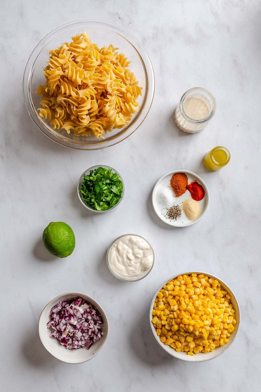 Ingredients for Elote Pasta Salad (Mexican Street Corn) measured out on a white surface.