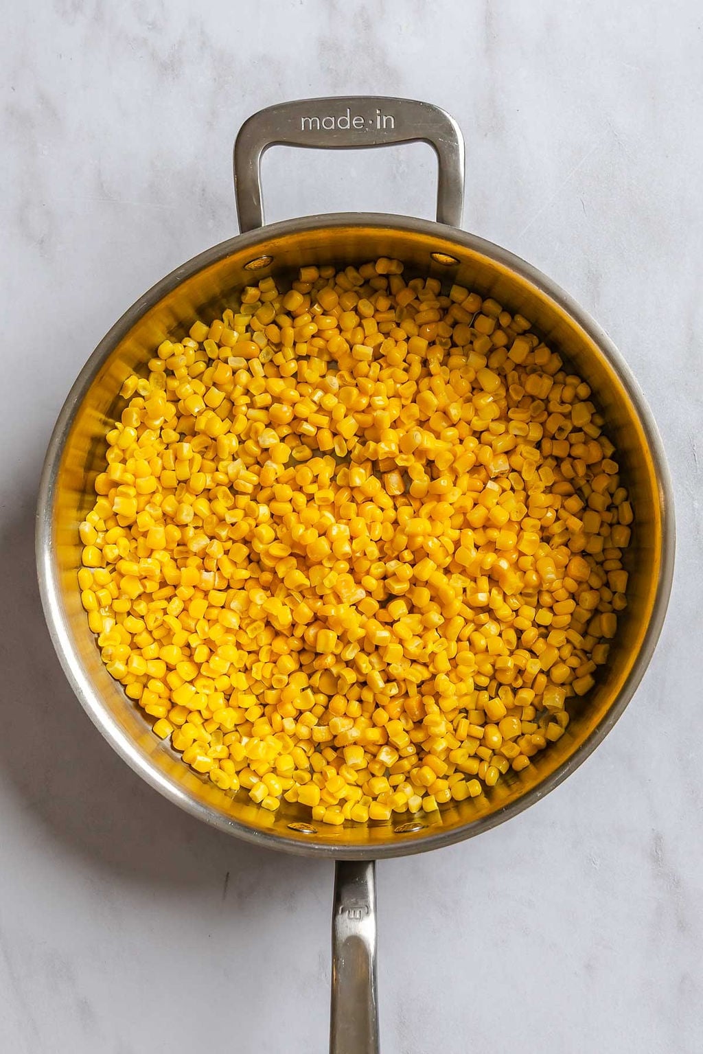 Process shot showing cooking corn in a pan.