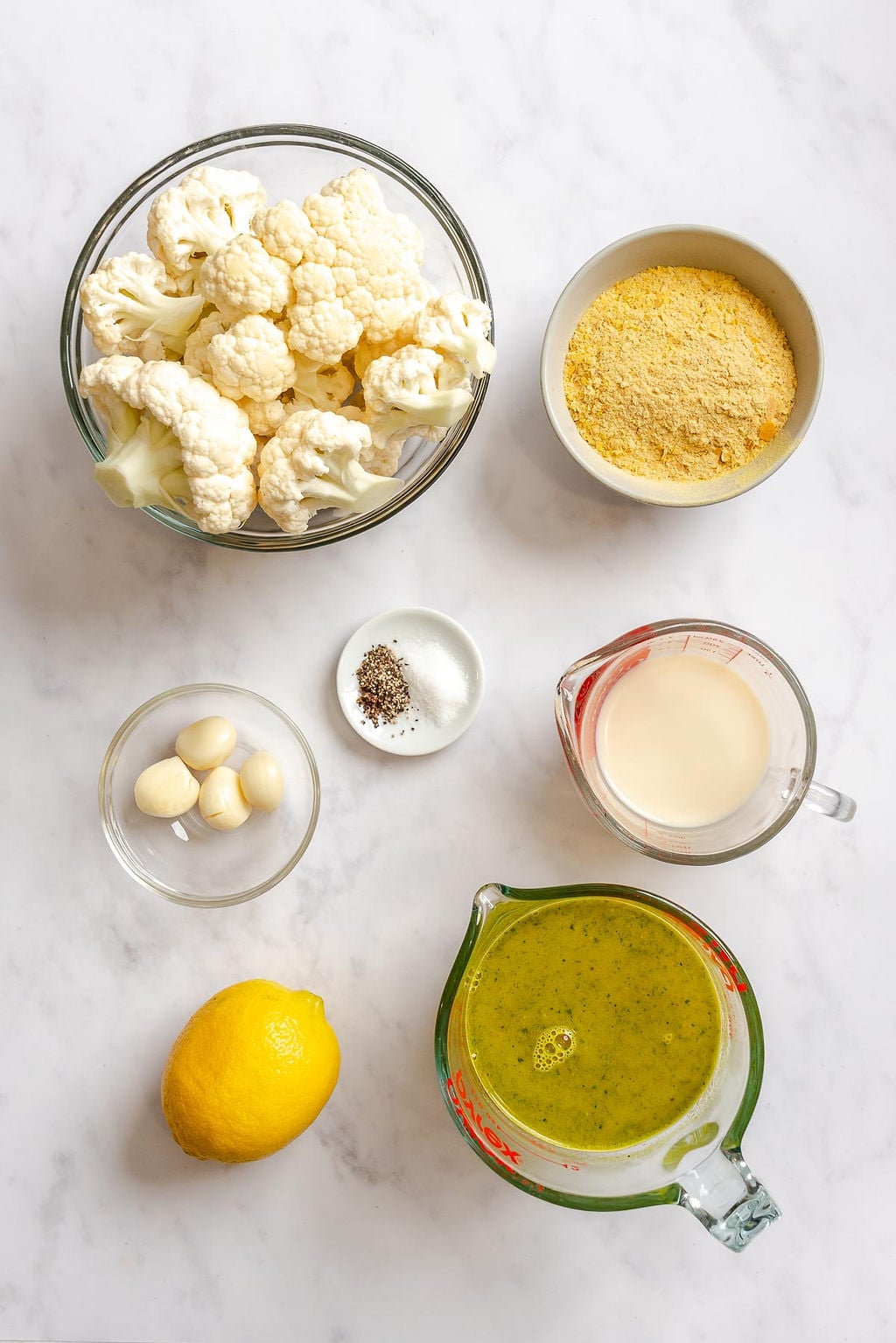 Ingredients for Healthy Cauliflower Alfredo Sauce measured out on a white surface.