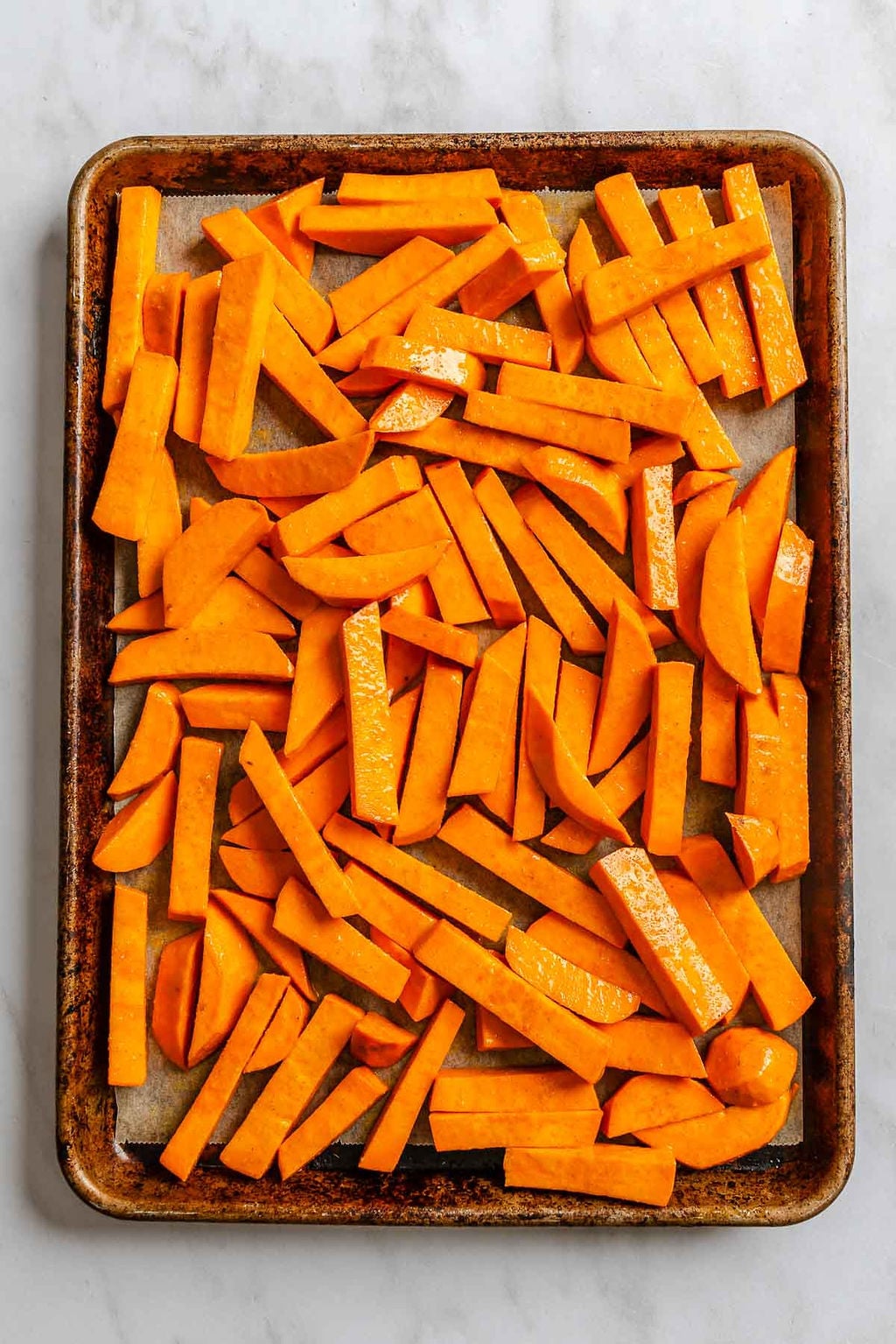 Process shot showing fries added to baking sheet.