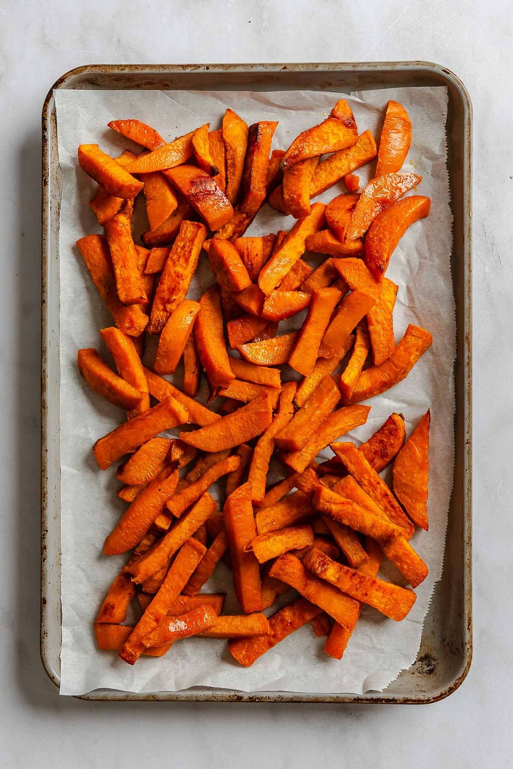 Process shot showing fries cooking on a baking sheet.