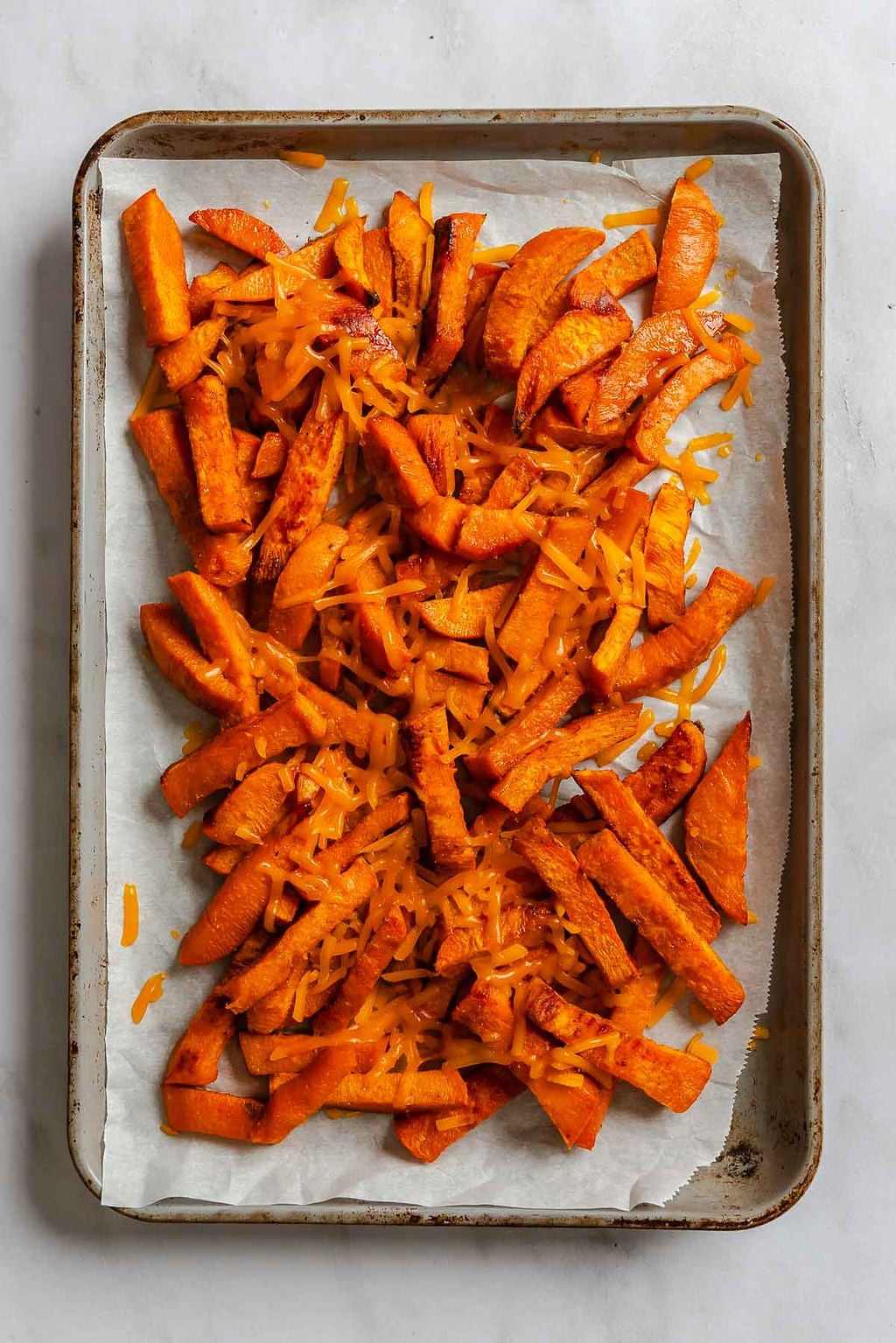 Process shot showing fries cooking on a baking sheet.