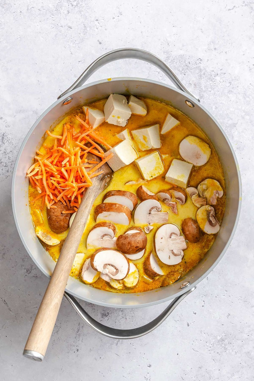 Process shot showing stirring Easy Vegan Laksa ingredients in a pot.