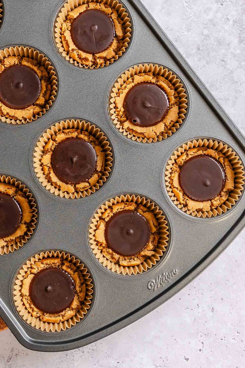 Process shot showing vegan chocolate added to muffin tin.